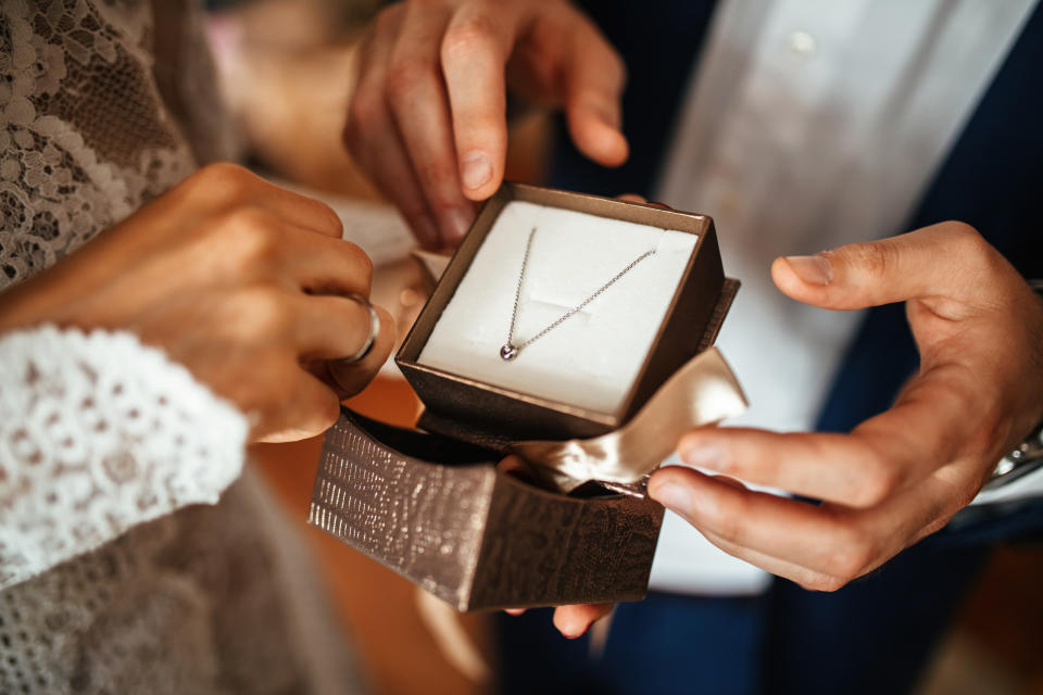 Close up of groom surprising his bride with a necklace on their wedding day.