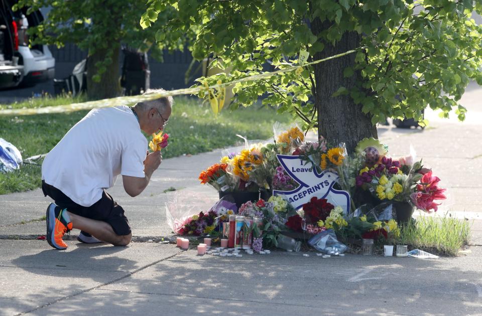 David Martinez of Buffalo places flowers at a memorial across the street from the Tops supermarket where a gunman killed ten people Saturday.