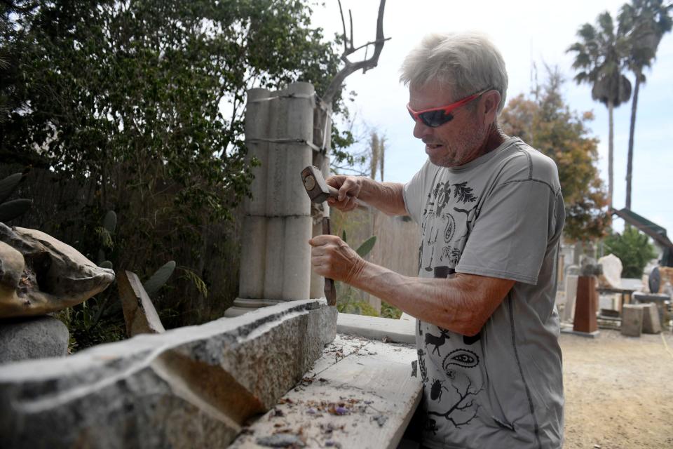Paul Lindhard, artist and founder of Art City in Ventura, chisels away on a granite sculpture on Friday, June 17, 2022. With the sale of the Art City site, Lindhard, fellow artists and supporters are hoping to preserve the unique site.