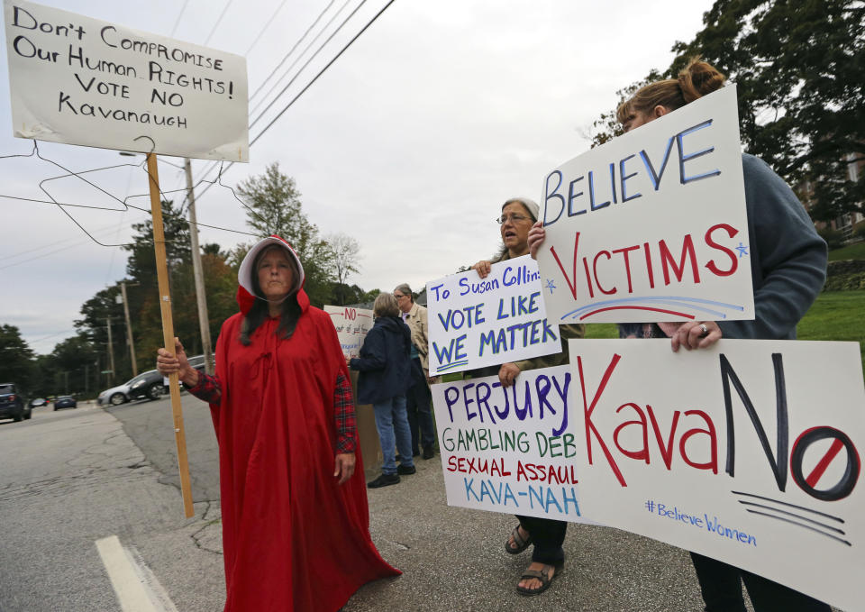 Demonstrators hold signs outside Saint Anselm College, Friday, Sept. 21, 2018, in Manchester, N.H., where U.S. Sen. Susan Collins, R-Maine, considered one of the few possible Republican "no" votes on Supreme Court nominee Brett Kavanaugh, is scheduled to speak. (AP Photo/Elise Amendola)