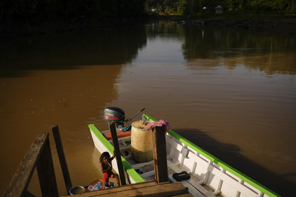 An Amerindian child brushes his teeth on the Barama River in Chinese Landing, Guyana, Monday, April 17, 2023. Called Chinese Landing for reasons residents no longer remember, the village is deep within lush forests of northern Guyana accessible primarily by riverboat. (AP Photo/Matias Delacroix)