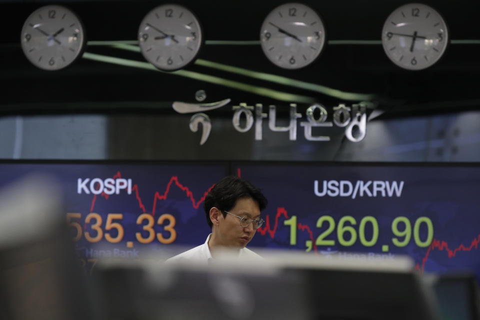 A currency trader walks by screens showing the Korea Composite Stock Price Index (KOSPI), left, and the foreign exchange rate between U.S. dollar and South Korean won at the foreign exchange dealing room in Seoul, South Korea, Tuesday, March 24, 2020. Asian stock markets gained Tuesday after the U.S. Federal Reserve promised support to the struggling economy as Congress delayed action on a $2 trillion coronavirus aid package. (AP Photo/Lee Jin-man)