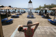 A woman takes a shower at a beach of Lagonissi village, a few miles southwest of Athens, on Thursday, July 29, 2021. One of the most severe heat waves recorded since 1980s scorched southeast Europe on Thursday, sending residents flocking to the coast, public fountains and air-conditioned locations to find some relief, with temperatures rose above 40 C (104 F) in parts of Greece and across much of the region. (AP Photo/Yorgos Karahalis)