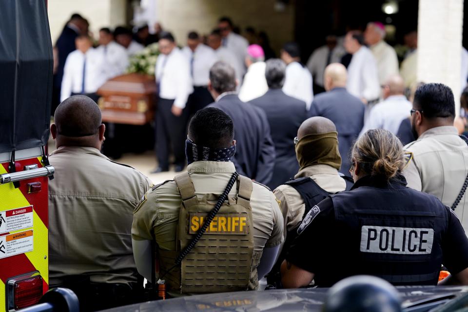 Law enforcement personnel look on as the caskets for Irma Garcia and husband Joe Garcia are carried by pallbearers following a joint service at Sacred Heart Catholic Church, Wednesday, June 1, 2022, in Uvalde, Texas. Irma Garcia was killed in last week's elementary school shooting; Joe Garcia died two days later.