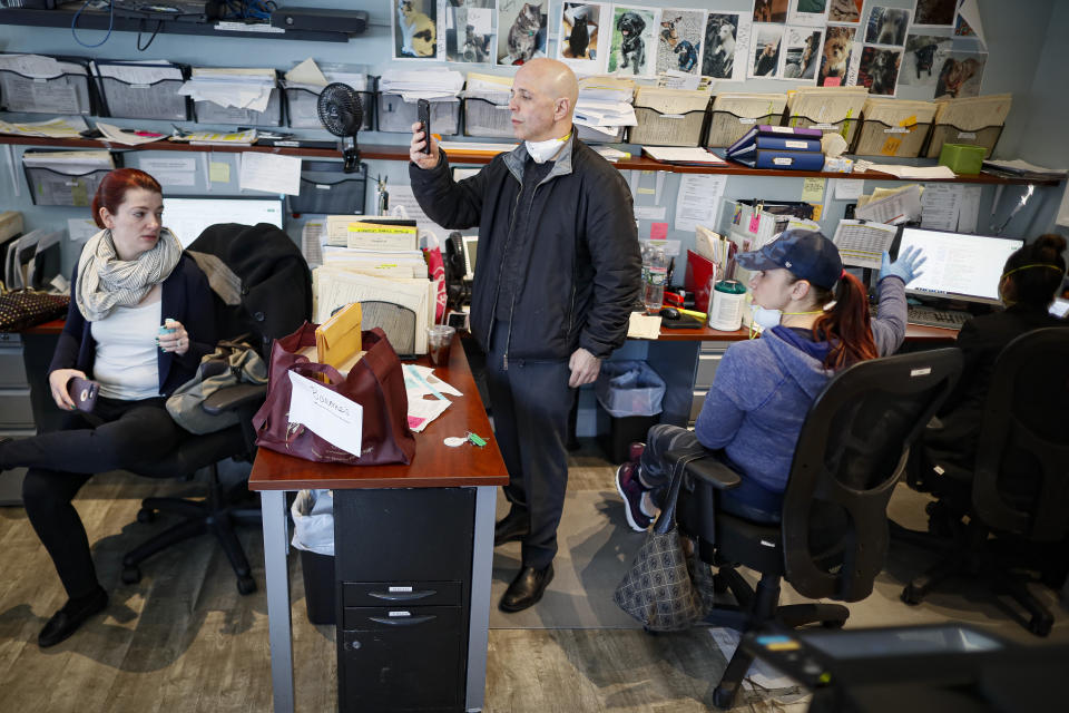 Pat Marmo, owner of Daniel J. Schaefer Funeral Home, center, takes a phone call in his office while handling the overflow of clients stemming from COVID-19 deaths, Thursday, April 2, 2020, in the Brooklyn borough of New York. He's apologizing to families at the start of every conversation for being unusually terse and insensitive, and begging them to insist hospitals hold their loved ones as long as possible. (AP Photo/John Minchillo)