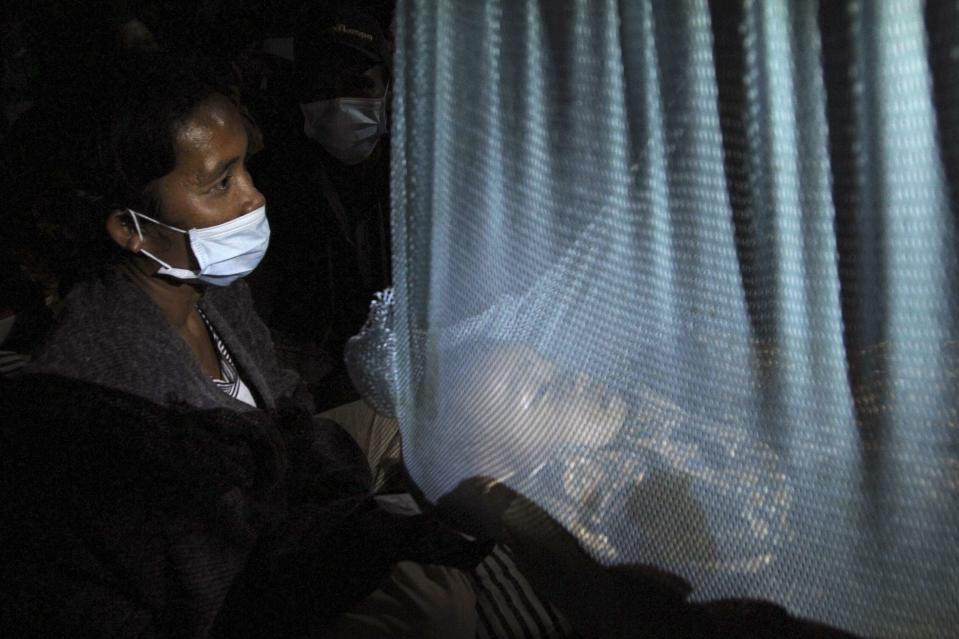A mother wearing a mask watches over her sleeping baby at an evacuation centre. (Reuters)