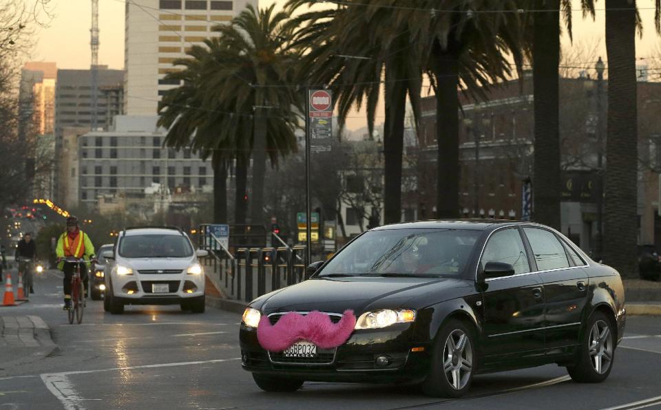 In this Jan. 17, 2013 photo, a Lyft car drives crosses Market Street in San Francisco. Fed up with traditional taxis, city dwellers are tapping their smartphones to hitch rides from strangers using mobile apps that allow riders and drivers to find each other. Internet-enabled ridesharing services such as Lyft, Uber and Sidecar are expanding rapidly in San Francisco, New York and other U.S. cities, billing themselves as a high-tech, low-cost alternative to cabs. (AP Photo/Jeff Chiu)