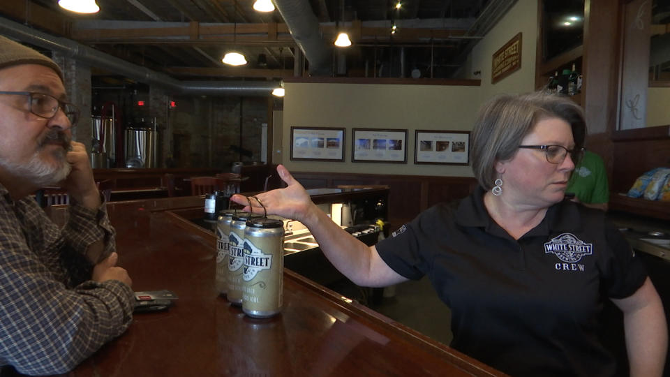 Tap room manager Rene Betancourt hands three "crowlers" of beer to Jim Judge at the White Street Brewing Company in Wake Forest, N.C., on Tuesday, March 17, 2020. With bars ordered close due to coronavirus, brewers are making sure their customers can enjoy some fresh suds. (AP Photo/Allen G. Breed)