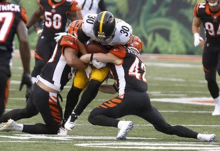 Oct 14, 2018; Cincinnati, OH, USA; Pittsburgh Steelers running back James Conner (30) is tackled by Cincinnati Bengals safety Clayton Fejedelem (42) and linebacker Jordan Evans (50) during the second half at Paul Brown Stadium. Mandatory Credit: David Kohl-USA TODAY Sports