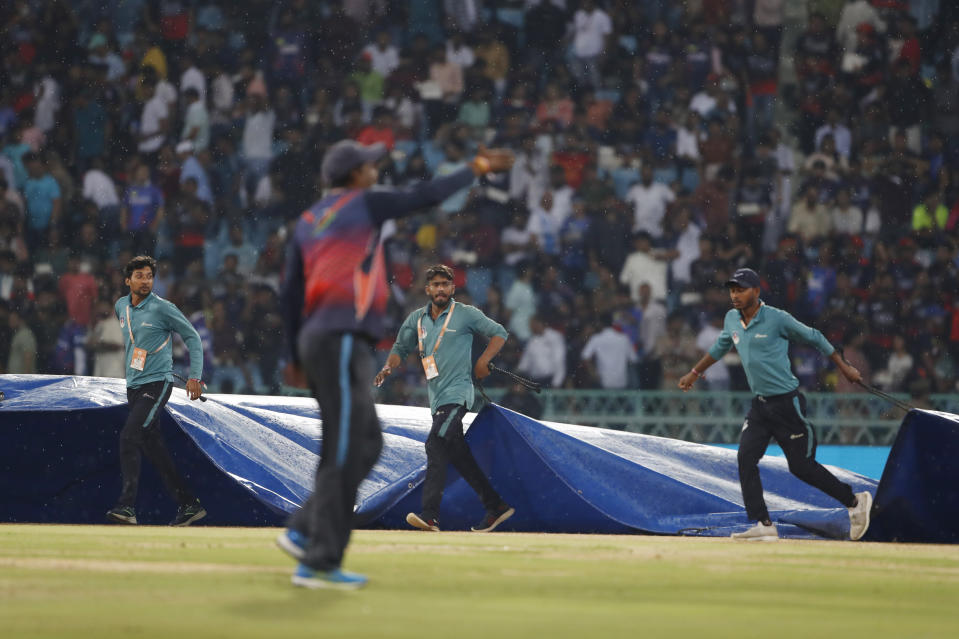 Ground's men cover the pitch following rains during the Indian Premier League (IPL) match between Lucknow Super Giants and Royal Challengers Bangalore in Lucknow, India, Monday, May 1, 2023. (AP Photo/Surjeet Yadav)