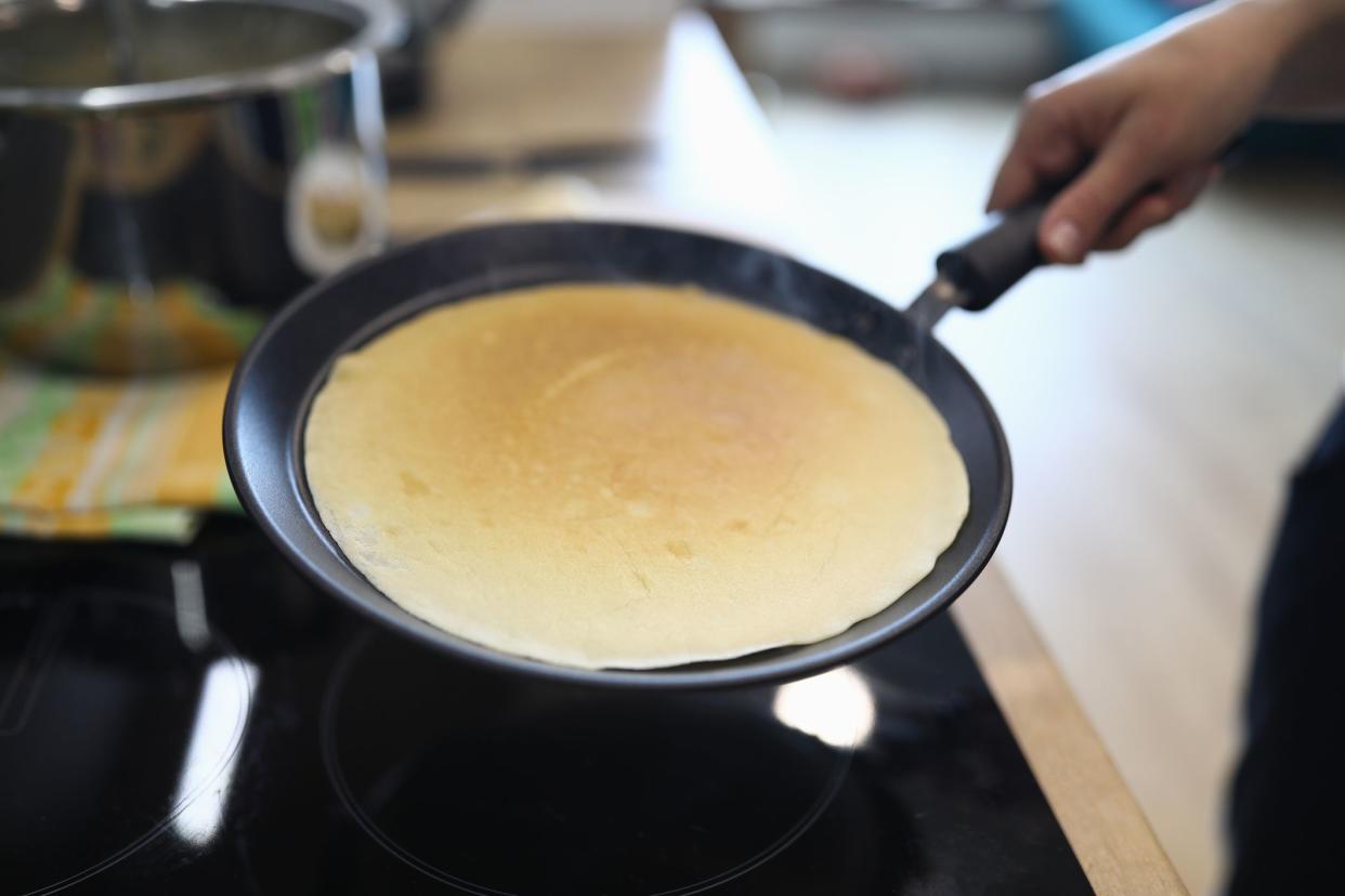 Hand holds pan with pancake, cooking at home. Available products, home recipes. Main types breakfast. Rules for working with toppings and assembly popular pies. Gluten free dough