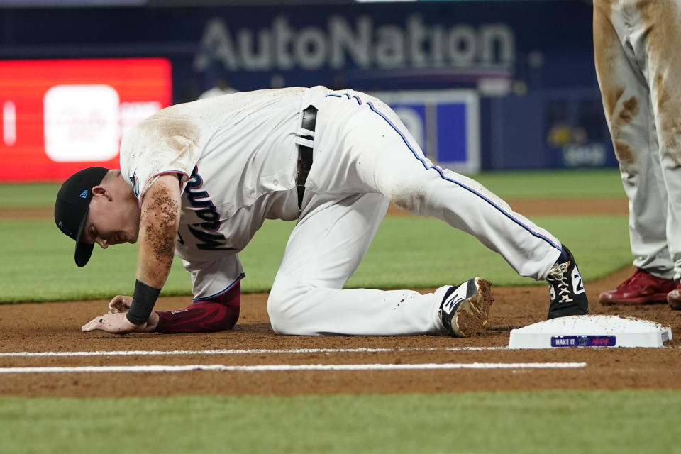 Miami Marlins first baseman Garrett Cooper gets up from the field after colliding with Philadelphia Phillies' Nick Castellanos during the first inning of a baseball game, Saturday, April 16, 2022, in Miami. (AP Photo/Lynne Sladky)