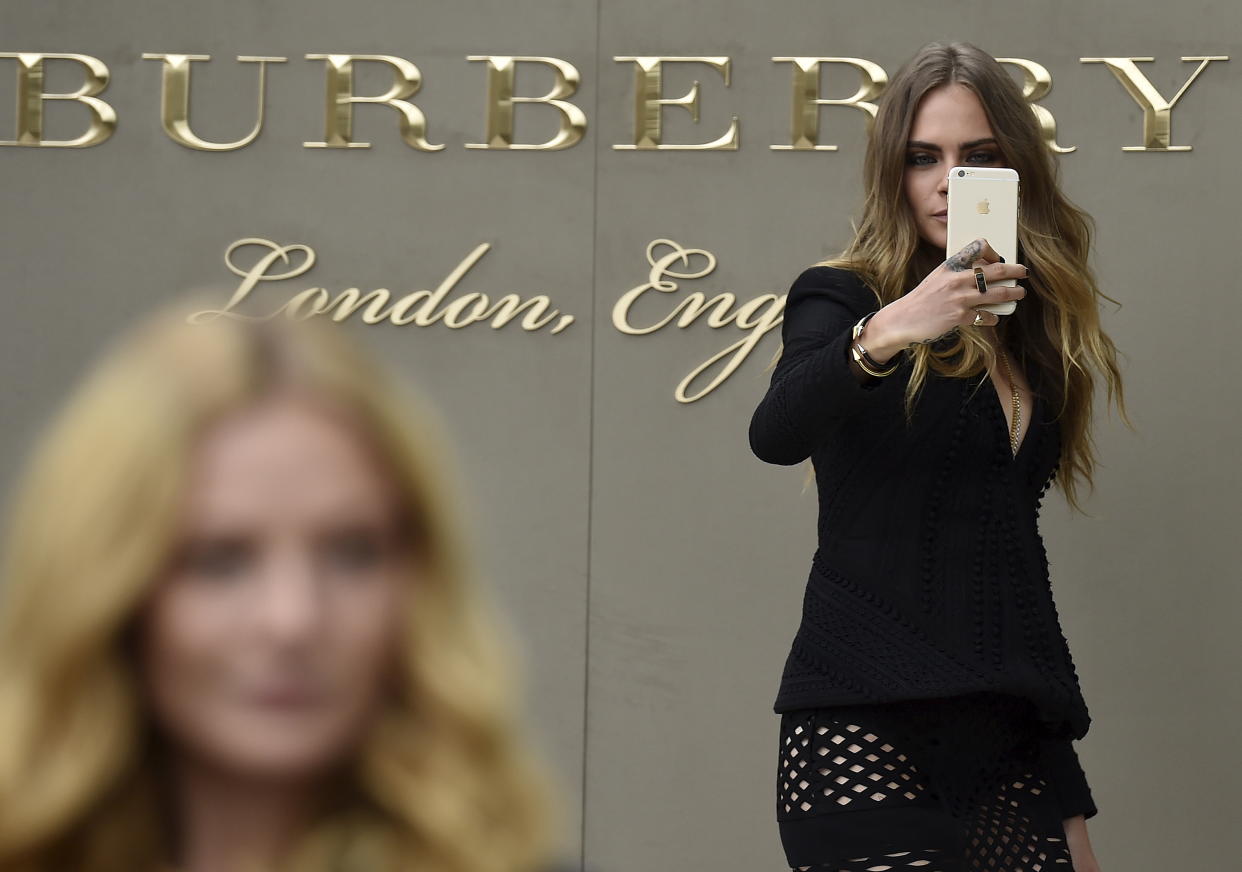 British model Cara Delevingne takes a selfie as she arrives for the Burberry Spring/Summer 2016 collection during London Fashion Week September 21, 2015. REUTERS/Toby Melville