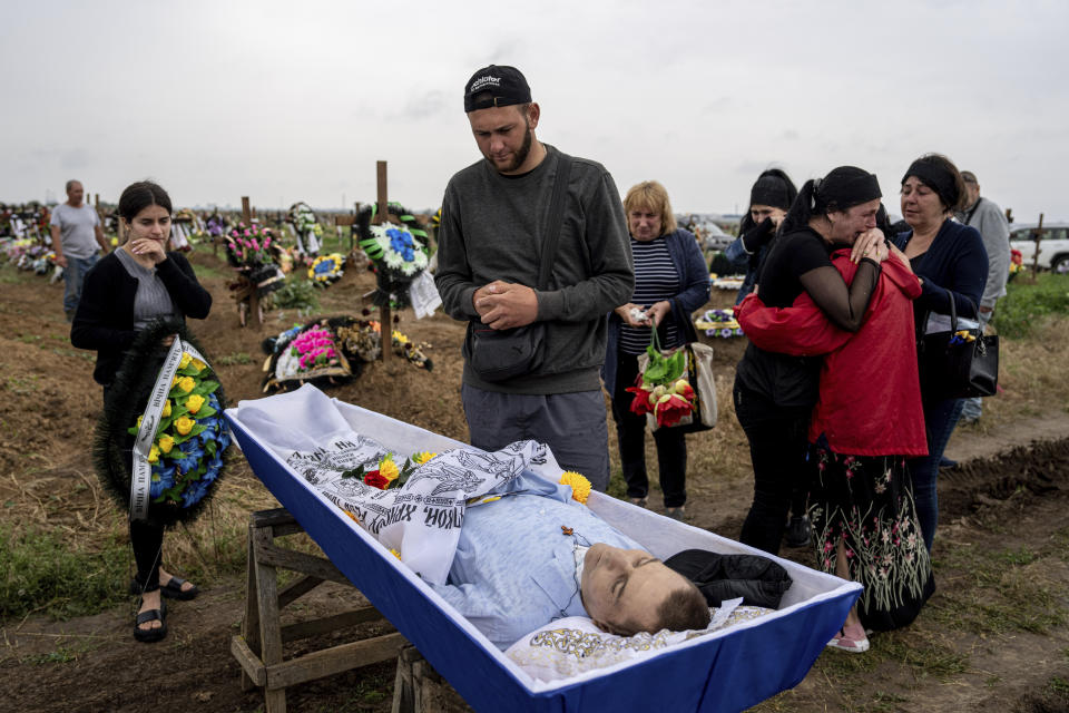 Vladislav Dementeev, residente en Kardashynka, llora durante el entierro de Vitali Holodniak, de 46 años, quien, según las autoridades ucranianas,fue asesinado por rusos en Kardashynka, en el cementerio de Jersón, Ucrania, el 14 de junio de 2023. (AP Foto/Evgeniy Maloletka)