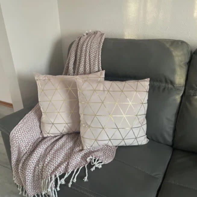 Two patterned throw pillows and a knitted blanket on a sofa, in a cozy home decor style