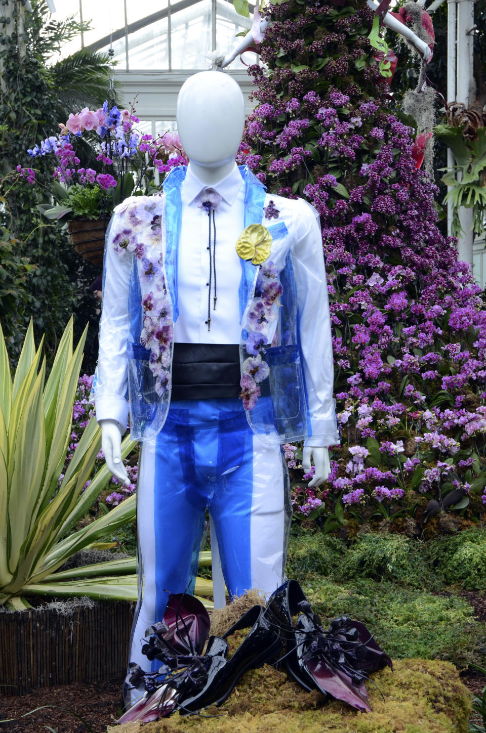 A fashion-creation inspired by nature from FLWR PSTL designed by Kristen Alpaugh in "The Orchid Show: Florals in Fashion" at The New York Botanical Garden, Saturday, Feb. 17, 2024, in the Bronx borough of New York. The mannequin in front wears an iridescent painted anthurium bloom and preserved orchid flowers. In back a mannequin wears a large cape of a variety of Phalaenopsis orchids in different shades of pink and purple, accented with mini ferns. (AP Photo/Pamela Hassell)