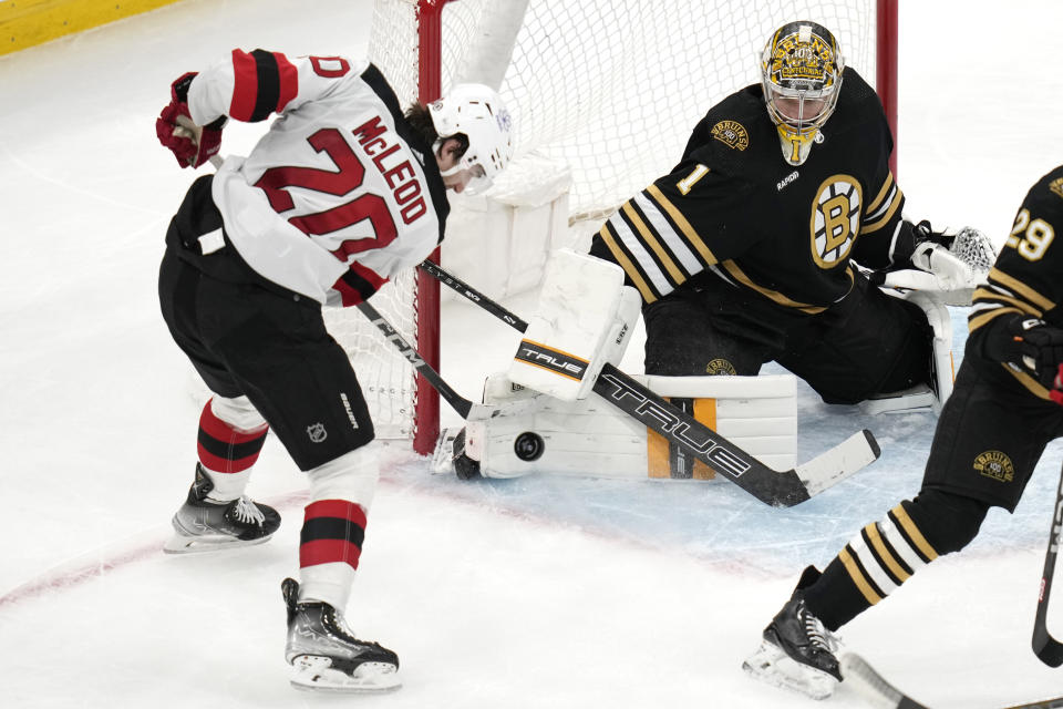 Boston Bruins goaltender Jeremy Swayman (1) makes a save on a shot by New Jersey Devils center Michael McLeod (20) during the third period of an NHL hockey game, Monday, Jan. 15, 2024, in Boston. (AP Photo/Charles Krupa)