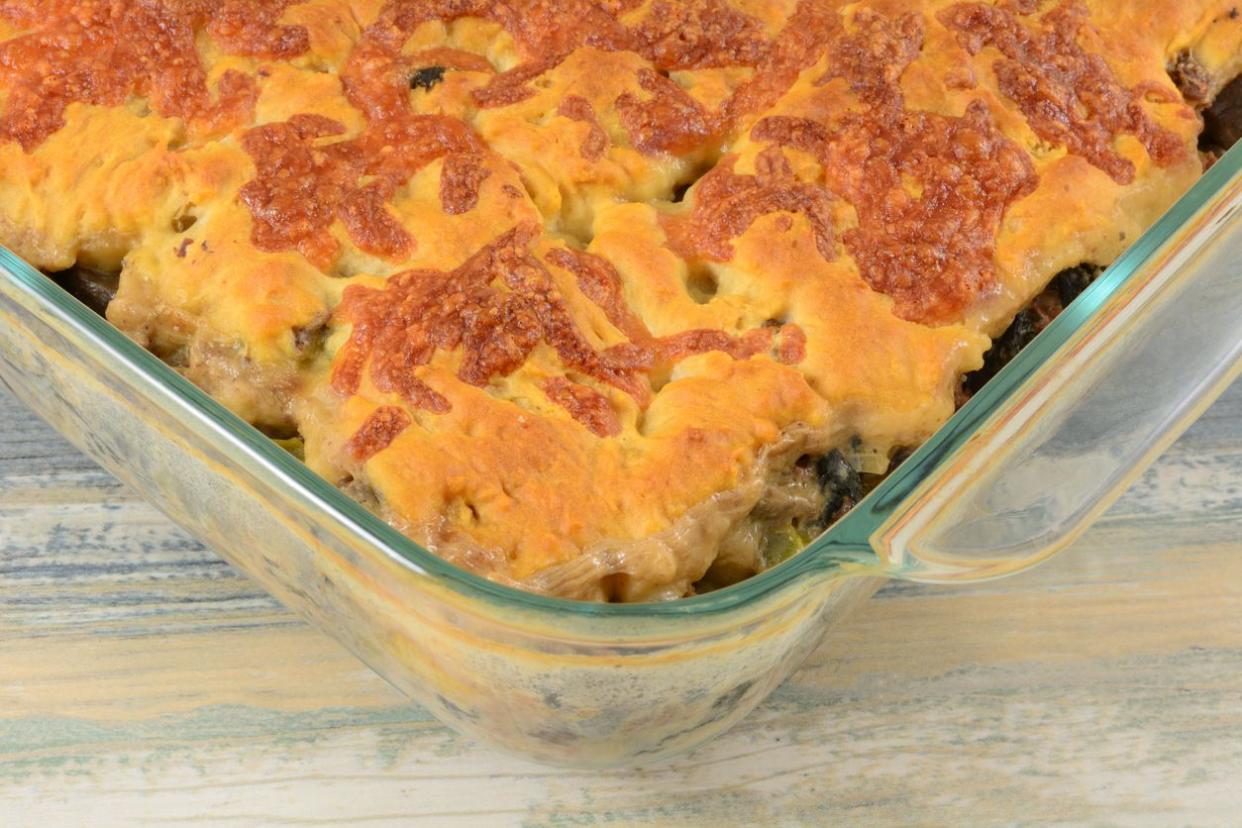 Baked beef and vegetable casserole with cheddar cheese biscuit crust in glass baking dish