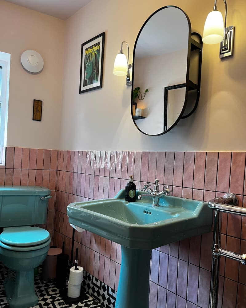 Green pedestal sink and toilet in bathroom with pink wall tiles.