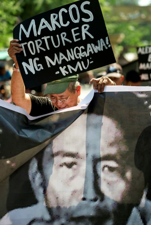 A protester holds a banner above the picture of the late Philippine dictator Ferdinand Marcos during a protest near the Malacanang palace in Manila on November 22, 2016