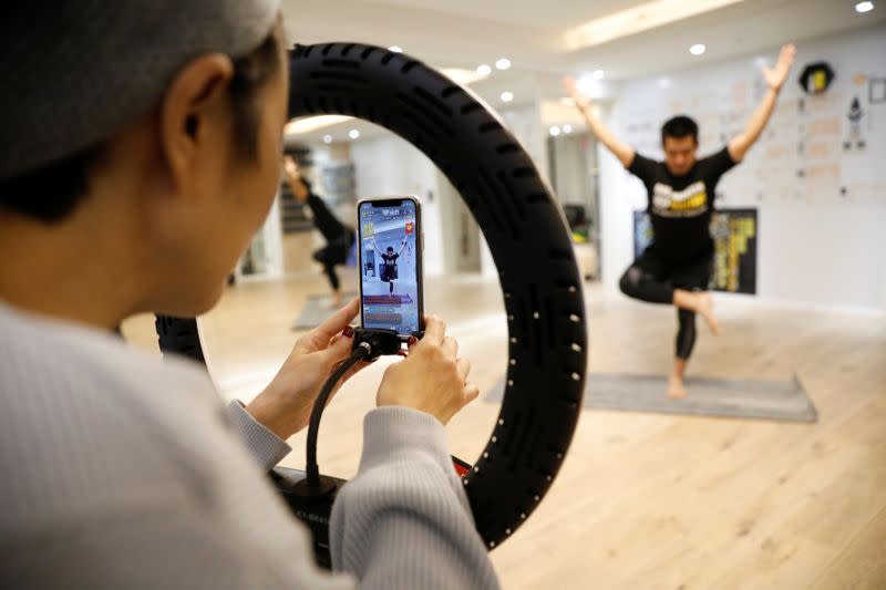 Liu Xiaojin, adjusts a phone during trainer Wang Kai's livestreamed gym class, as the country is hit by an outbreak of the new coronavirus, in Beijing