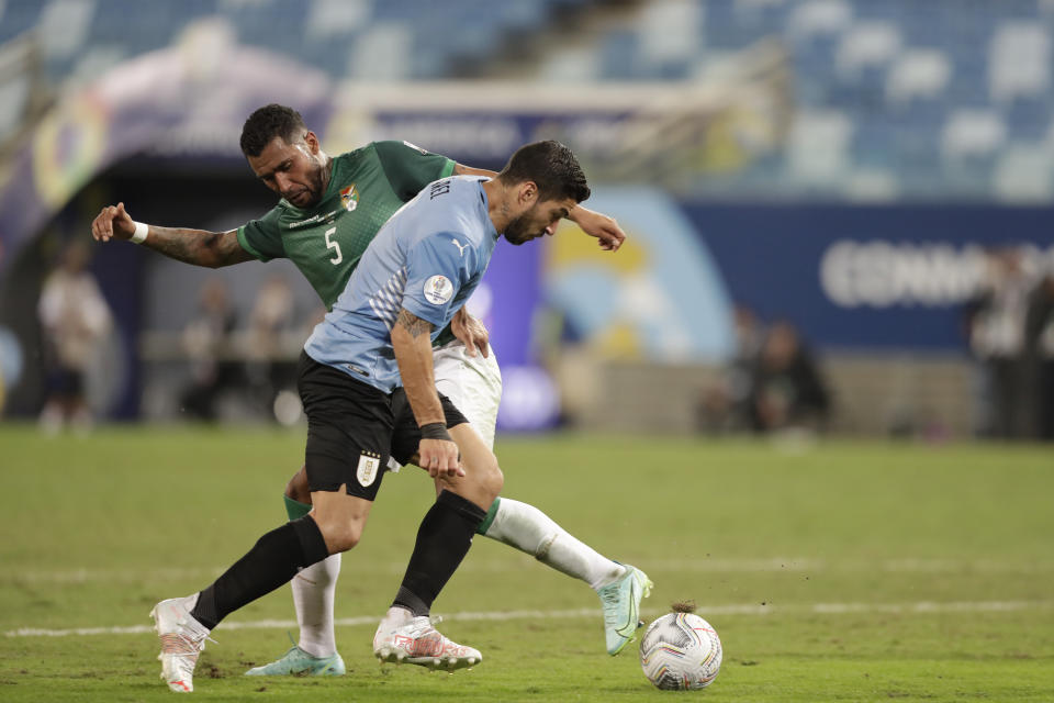 Uruguay's Luis Suarez, front, fights for the ball with Bolivia's Adrian Jusino during a Copa America soccer match at Arena Pantanal in Cuiaba, Brazil, Thursday, June 24, 2021. (AP Photo/Andre Penner)