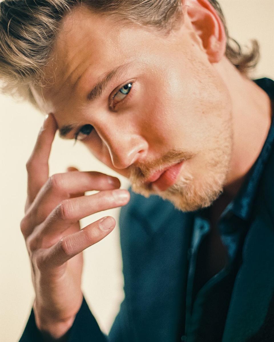 Austin Butler puts a finger to his forehead for a portrait.