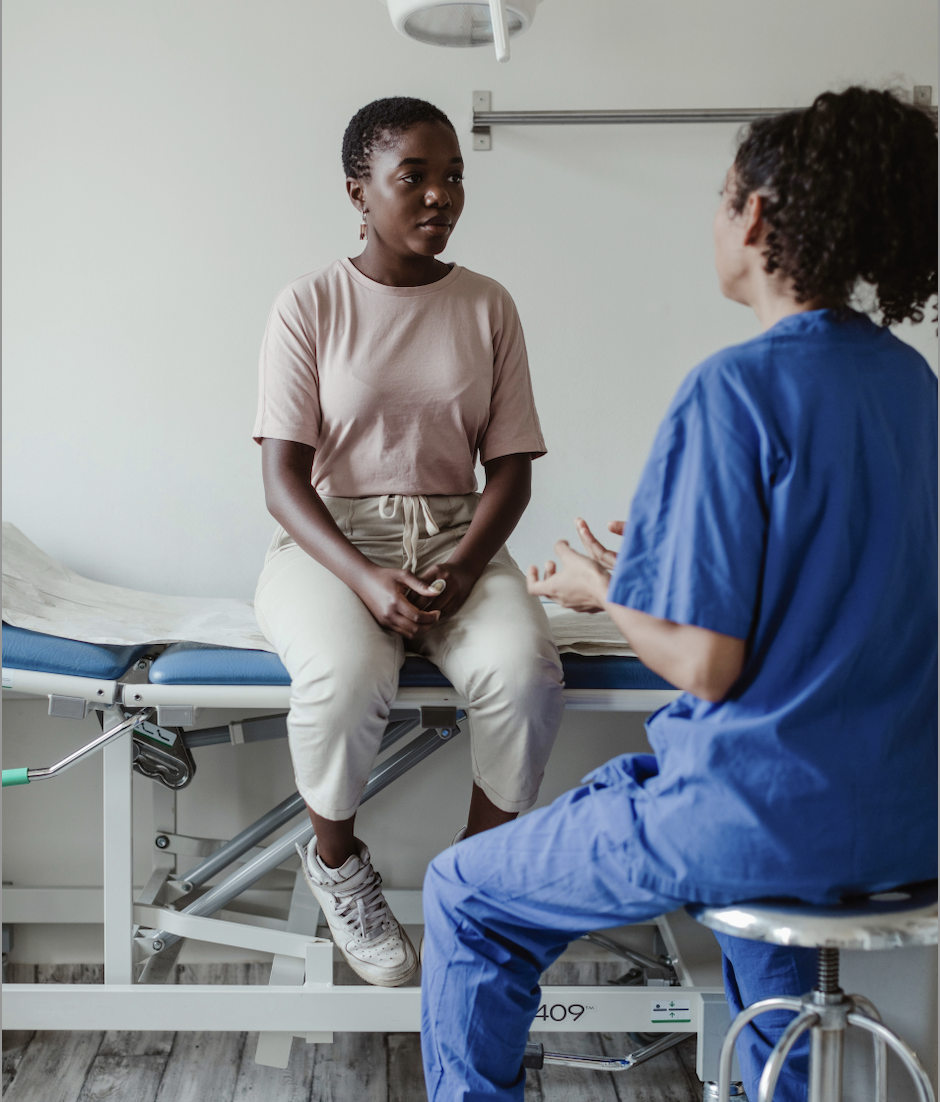 Black woman sitting in a doctor's office listening to a nurse