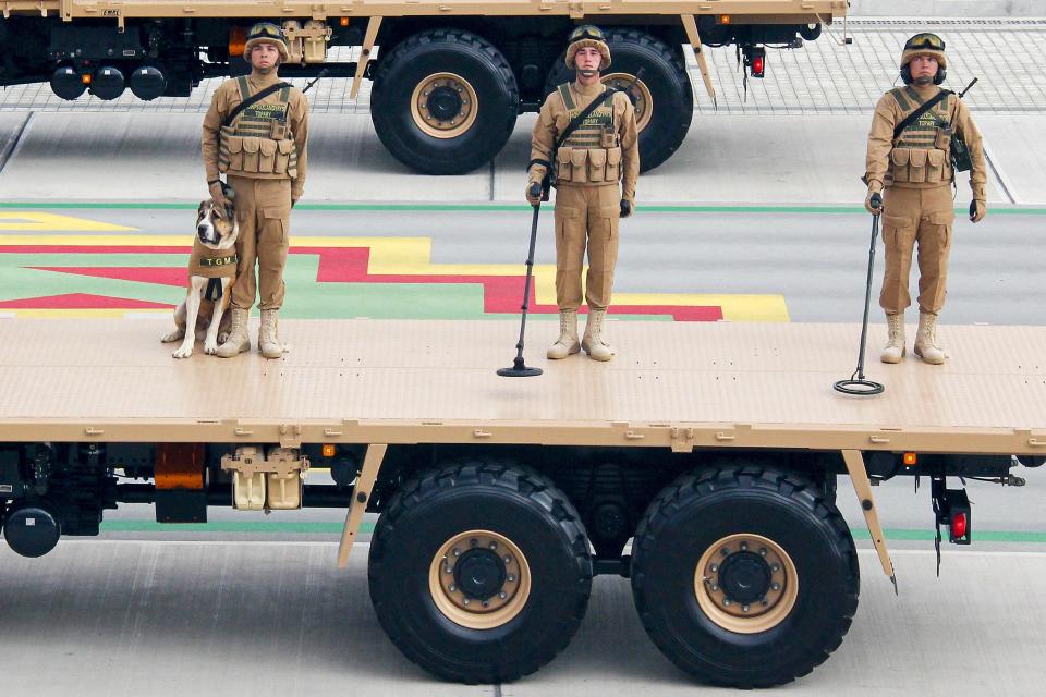 Turkmenistan's army demining soldiers, one of them with a shepherd dog Alabay, stand on a planform during a military parade celebrating the country's 30th independence anniversary in Ashgabat, Turkmenistan, Monday, Sept. 27, 2021. The pomp-filled parade took place in Ashgabat, the capital of the gas-rich former Soviet nation in Central Asia. Aside from troops and military equipment, the parade featured employees of state ministries and institutions demonstrating their achievements and Alabai dogs, which accompanied soldiers on military vehicles. (AP Photo/Alexander Vershinin)