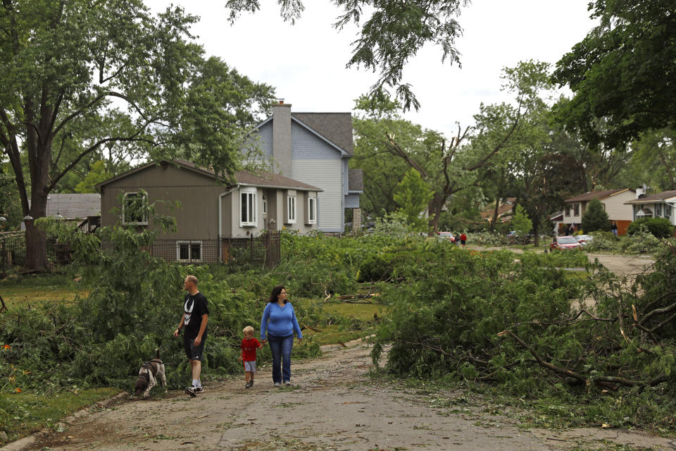 Residents walks through the neighborhood after a tornado passed through the area on Monday, June 21, 2021 in Woodridge, Ill. (AP Photo/Shafkat Anowar)