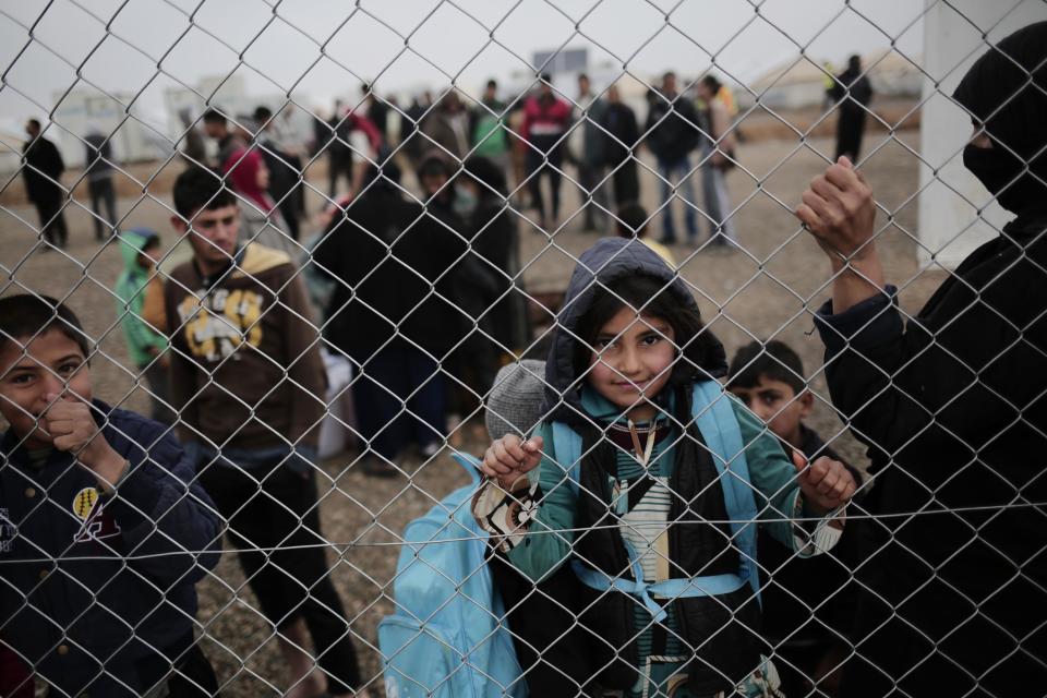 A child looks at a photographer as displaced people wait for aid at a camp east of Mosul, Iraq, Wednesday, Feb. 15, 2017. The United Nations says they are temporarily pausing aid operations to neighborhoods in eastern Mosul retaken from the Islamic State group for security reasons as IS insurgent and counter attacks continue to inflict heavy civilian casualties there.(AP Photo/Bram Janssen)