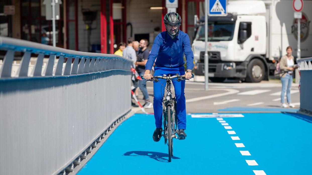 Oberbürgermeister Boris Palmer rollt über die erste beheizbare Radbrücke in Tübingen.