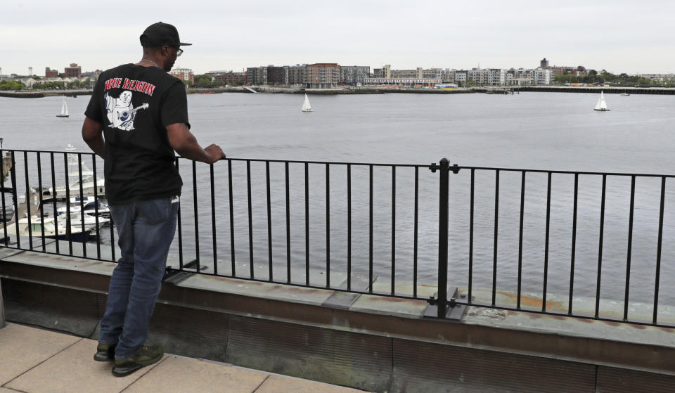 In this Tuesday June 4, 2019 photograph, Sean Ellis watches boats sailing on Boston Harbor from the roof deck of his attorney Rosemary Scapicchio's office after an afternoon indoor meeting in Boston. During the 22 years he spent in prison after being convicted of killing a Boston police detective, Ellis believed there was something suspicious about the officers who led the murder investigation. He just couldn’t prove it. It would take years of digging and scores of public information requests from his attorneys to uncover evidence that several officers investigating the 1993 murder case were involved in criminal activity, information that wasn’t shared with the defense. (AP Photo/Charles Krupa)