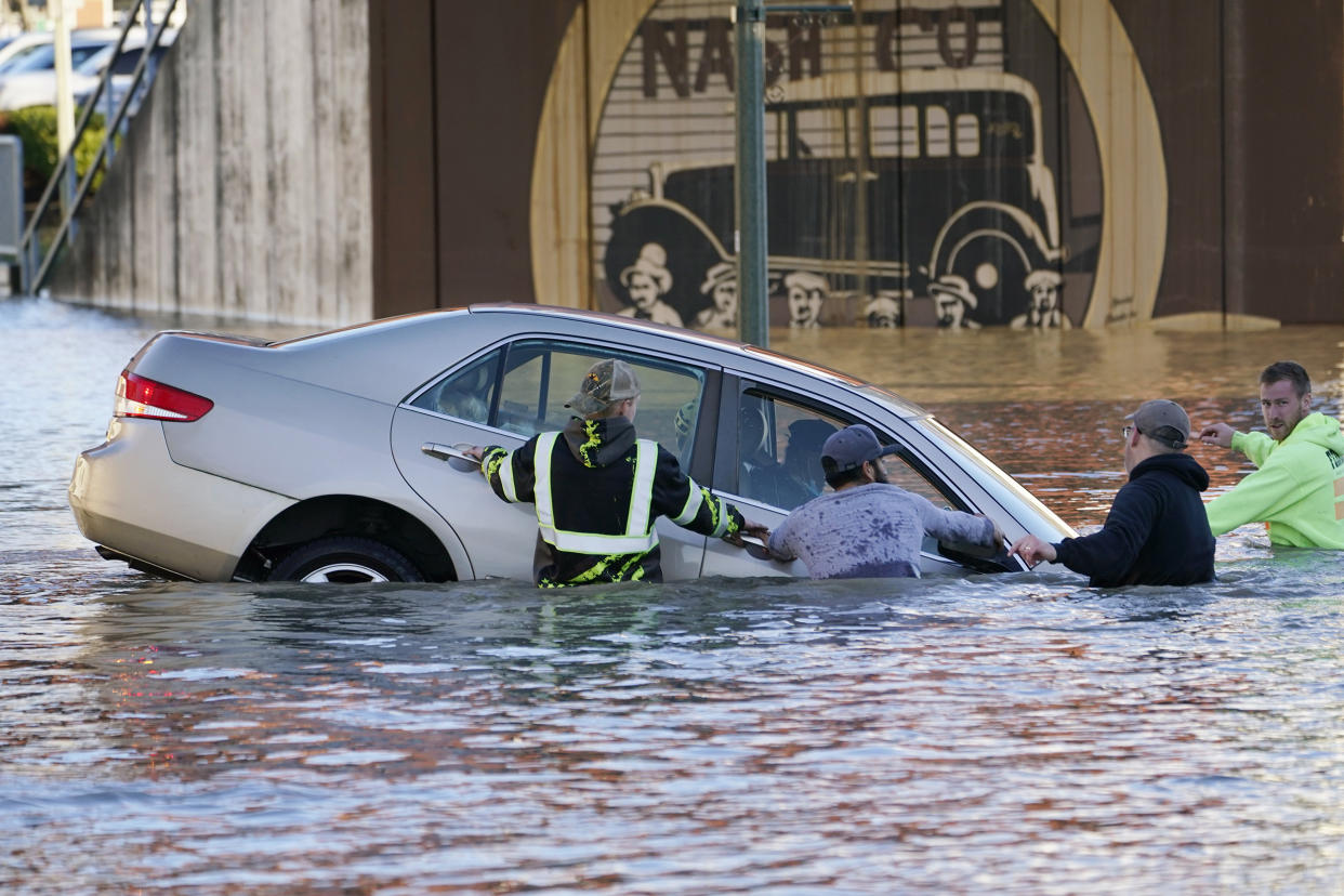 Image: Passersby surround a car whose driver went past a barricade and into the flooded Nooksack River on Nov. 16, 2021, in Ferndale, Wash. (Elaine Thompson / AP)