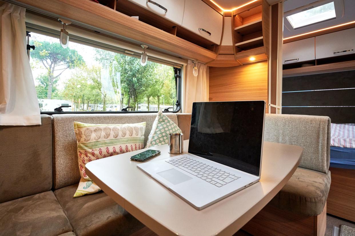 Arbeiten Mobile Work vom Urlaub aus auf dem Campingplatz mit einem Laptop in einem Wohnwagen Wohnmobil