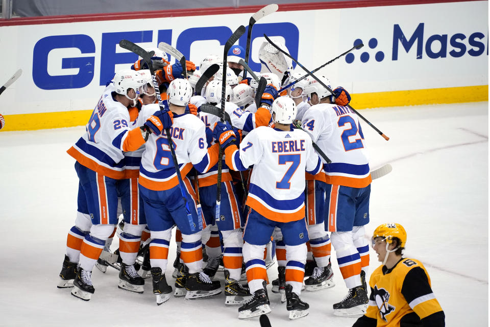 Pittsburgh Penguins' John Marino (6) skates to the locker room as the New York Islanders celebrate a game-winning overtime goal by Kyle Palmieri in Game 1 of an NHL hockey Stanley Cup first-round playoff series in Pittsburgh, Sunday, May 16, 2021. The Islanders won 4-3. (AP Photo/Gene J. Puskar)