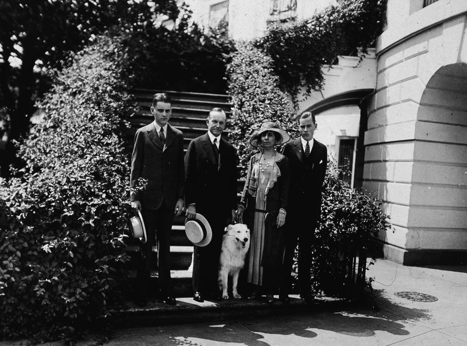 President Calvin Coolidge stands outdoors with his wife Grace, their two sons, and their pet white collie Rob Roy in the 1920s.