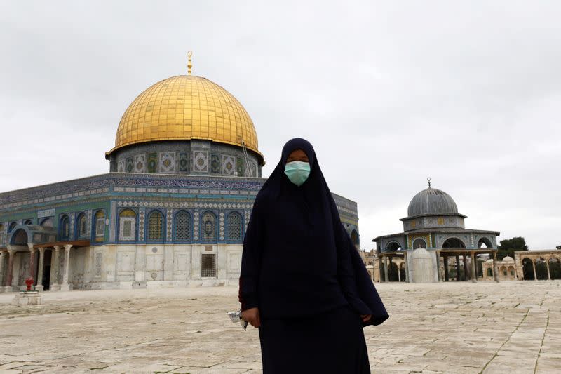 FILE PHOTO: A worshipper wearing a mask walks in front of the Dome of the Rock in the compound known to Muslims as Noble Sanctuary and to Jews as Temple Mount, in Jerusalem's Old City