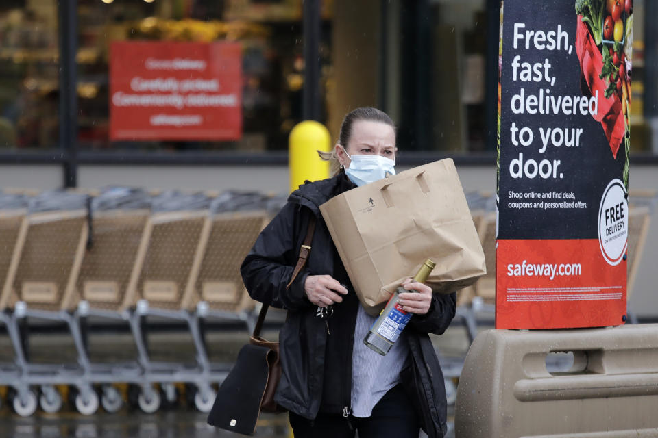 In this Monday, March 30, 2020, photo, a shopper leaves a grocery story with food packed in a paper bag, where the dime-per-bag fee has been waved during the coronavirus outbreak, in Seattle. Just weeks earlier, cities and even states across the U.S. were busy banning straws, limiting takeout containers and mandating that shoppers bring reusable bags or pay a small fee. Grocery clerks are nervous that the virus could linger on reusable fabric bags and their unions are backing them up with demands to end plastic bag fees and suspend bag bans. The plastics industry has seized the moment, lobbying to overturn existing bans on single-use plastics. (AP Photo/Elaine Thompson)