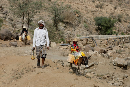 A man walks as women ride donkeys after they collected water from a well in al-Jaraib, in the northwestern province of Hajjah, Yemen, February 20, 2019. In water-scarce Yemen, with many parts of the country needing pumps to bring water to the surface, water prices have increased dramatically under years of fuel shortages. In al-Jaraib, well water is available for free. Those who can afford to buy water from tankers which fill up from a pond 7 km from the village. REUTERS/Khaled Abdullah