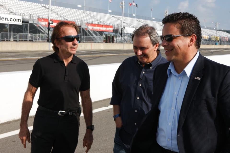 Emerson Fittipaldi, left, walks down the frontstretch at Watkins Glen International with WGI President Michael Printup, right, and Reginaldo Leme, the interviewer for the documentary on Fittipaldi's 1970 Formula One victory at the track, in July of 2010.