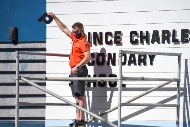 Vice-principal Mike Nelson of Creston Valley Secondary School in Creston, B.C., removes the first letter of Prince Charles's name from the school's exterior signage at a ceremony last Friday. (Jeff Banman - image credit)