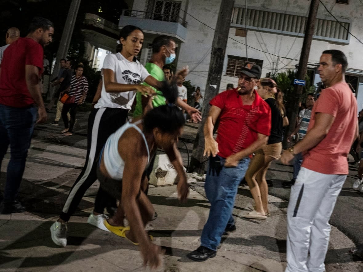 A plainclothes police officer throws a woman to the ground during an anti-government protest in Havana, Cuba, on Oct 1, 2022. A Cuban-Canadian says she's been banned from returning to Cuba because of her social media posts critical of the country's one-party state. (Ramon Espinosa/The Associated Press - image credit)