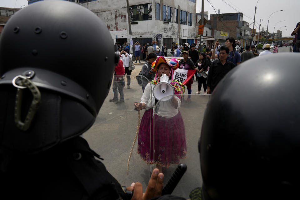 An anti-government protester challenges police surrounding the San Marcos University in Lima, Peru, Saturday, Jan. 21, 2023. Police evicted from the university grounds protesters who arrived from Andean regions seeking the resignation of President Dina Boluarte, the release from prison of ousted President Pedro Castillo and immediate elections. (AP Photo/Martin Mejia)