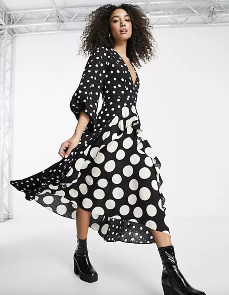 model with long curly hair in black boots and black and white polka dot Topshop Mixed Spot Long Sleeve Ruffle Midi Dress (Photo via ASOS)