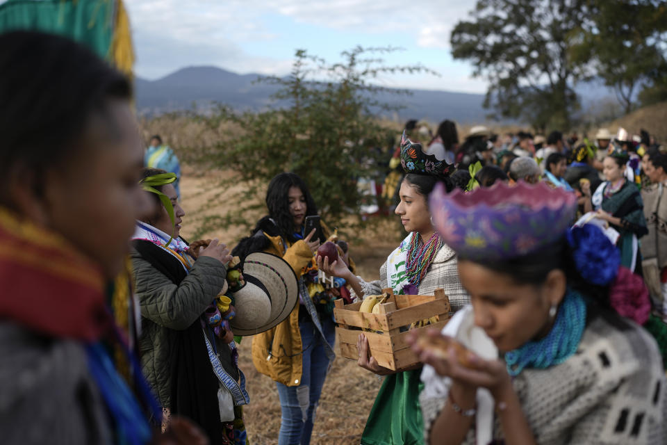 Los indígenas purépechas reparten frutas después de realizar una ceremonia en honor al sol en Ocumicho, la mañana después de caminar desde Erongarícuaro con una llama que su comunidad había mantenido viva durante un año en el estado de Michoacán, México, el jueves 1 de febrero de 2024. (AP Foto/Eduardo Verdugo)