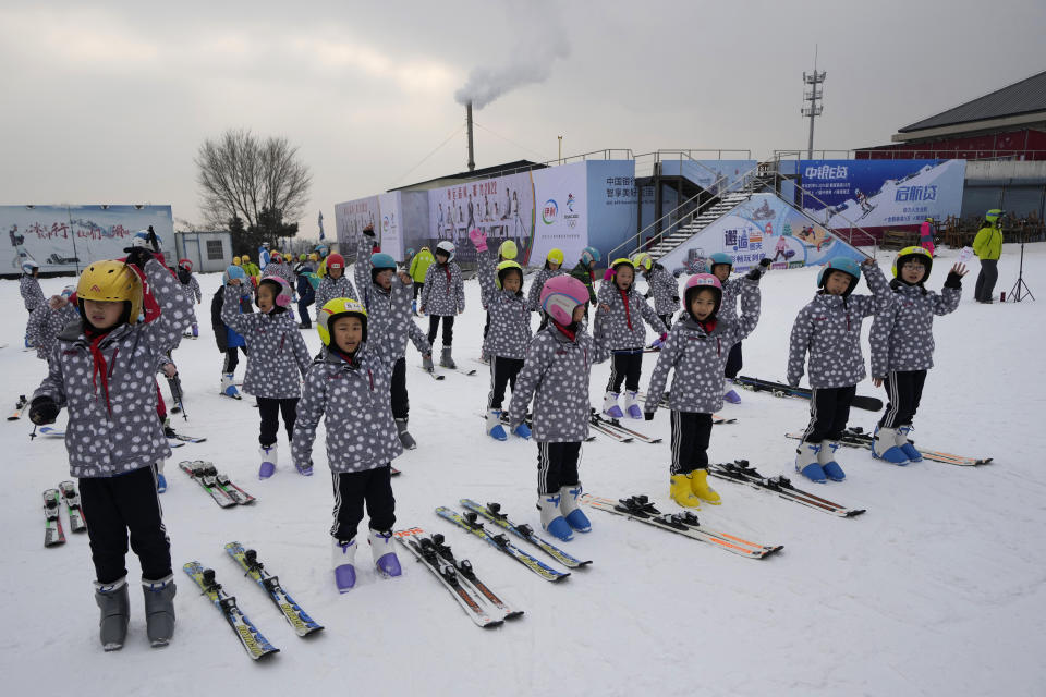 School children warm up before taking ski lessons at the Vanke Shijinglong Ski Resort in Yanqing on the outskirts of Beijing, China, Thursday, Dec. 23, 2021. The Beijing Winter Olympics is tapping into and encouraging growing interest among Chinese in skiing, skating, hockey and other previously unfamiliar winter sports. It's also creating new business opportunities. (AP Photo/Ng Han Guan)