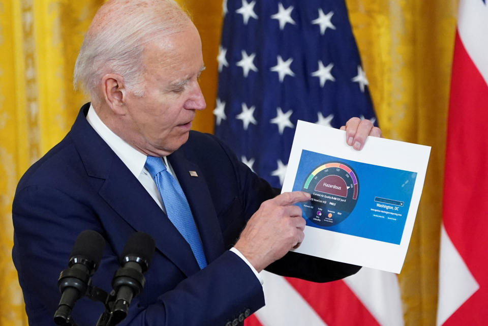 President Biden shows off a printout of the U.S. Air Quality Index for Washington, DC, at the White House on Thursday.  (Kevin Lamarque/Pool via Reuters).