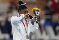 Simone Biles, of the United States, removes her face mask on the podium after winning the bronze medal on the balance beam during the artistic gymnastics women's apparatus final at the 2020 Summer Olympics, Tuesday, Aug. 3, 2021, in Tokyo, Japan. (AP Photo/Natacha Pisarenko)