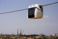 A small, four-seat pod made by uSky glides above the sands of a test track in Sharjah, United Arab Emirates, Thursday, Oct. 28, 2021. The futuristic transit solution is being promoted by a Belarusian firm that hopes to secure contracts here in the near future. However, uSky has ties back to a Belarusian investment firm called SkyWay that has seen multiple nations in Europe and elsewhere issue warnings to investors that they "may be involved in a scam." (AP Photo/Jon Gambrell)